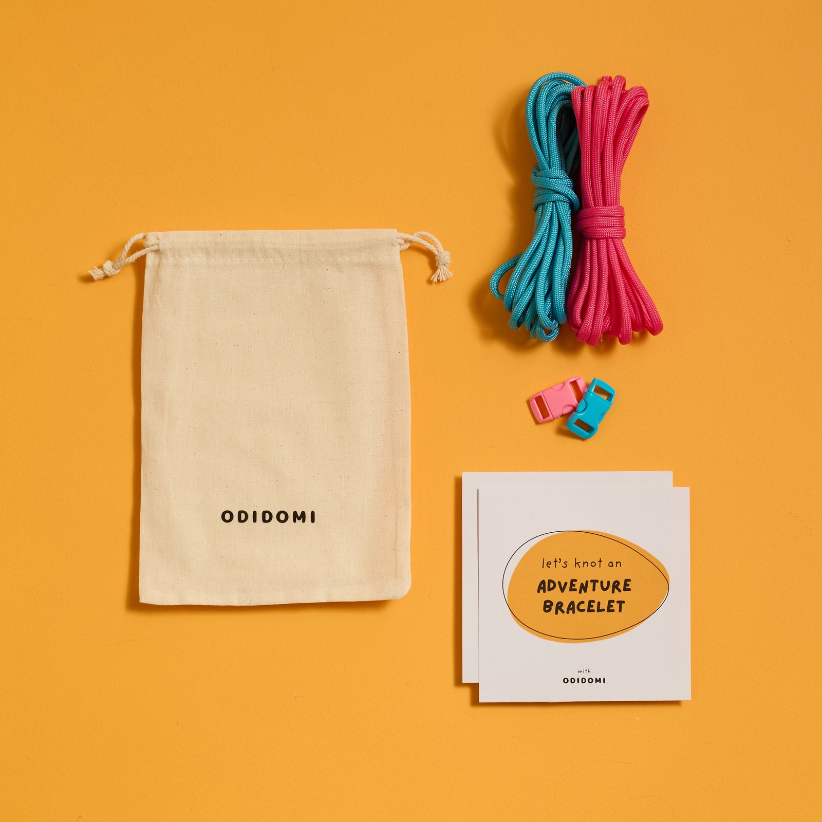 Flat lay of the complete ODIDOMI Adventure Bracelet Kit in the pink and blue color option.