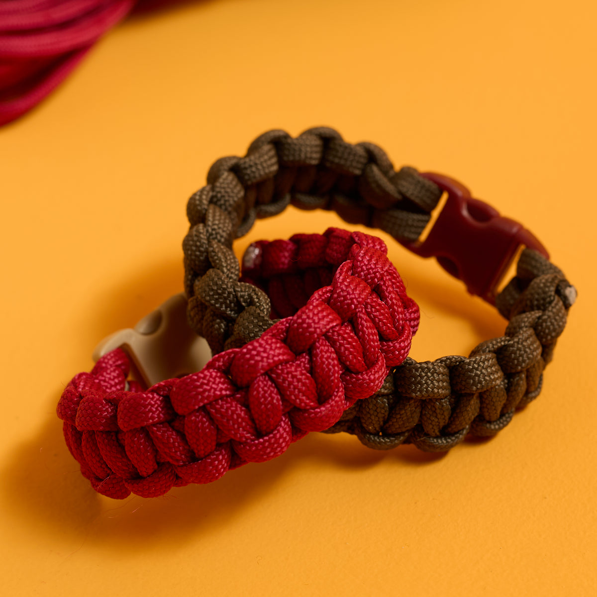 Close-up of finished buckled bracelets from the ODIDOMI Adventure Bracelet Kit in charcoal and red.