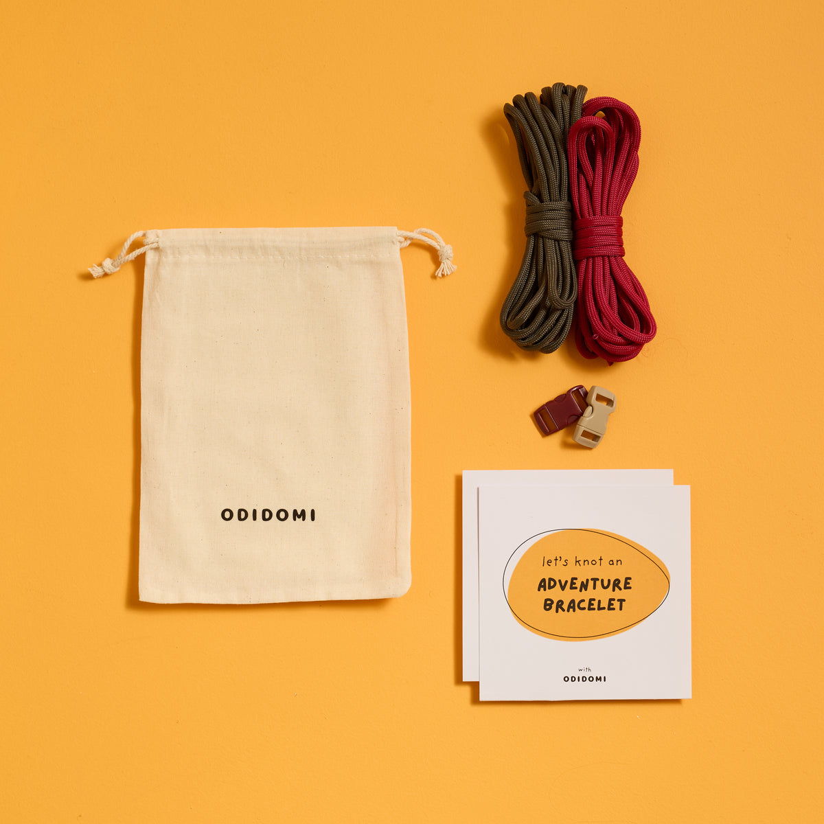 Flat lay of the complete ODIDOMI Adventure Bracelet Kit in the charcoal and red color option