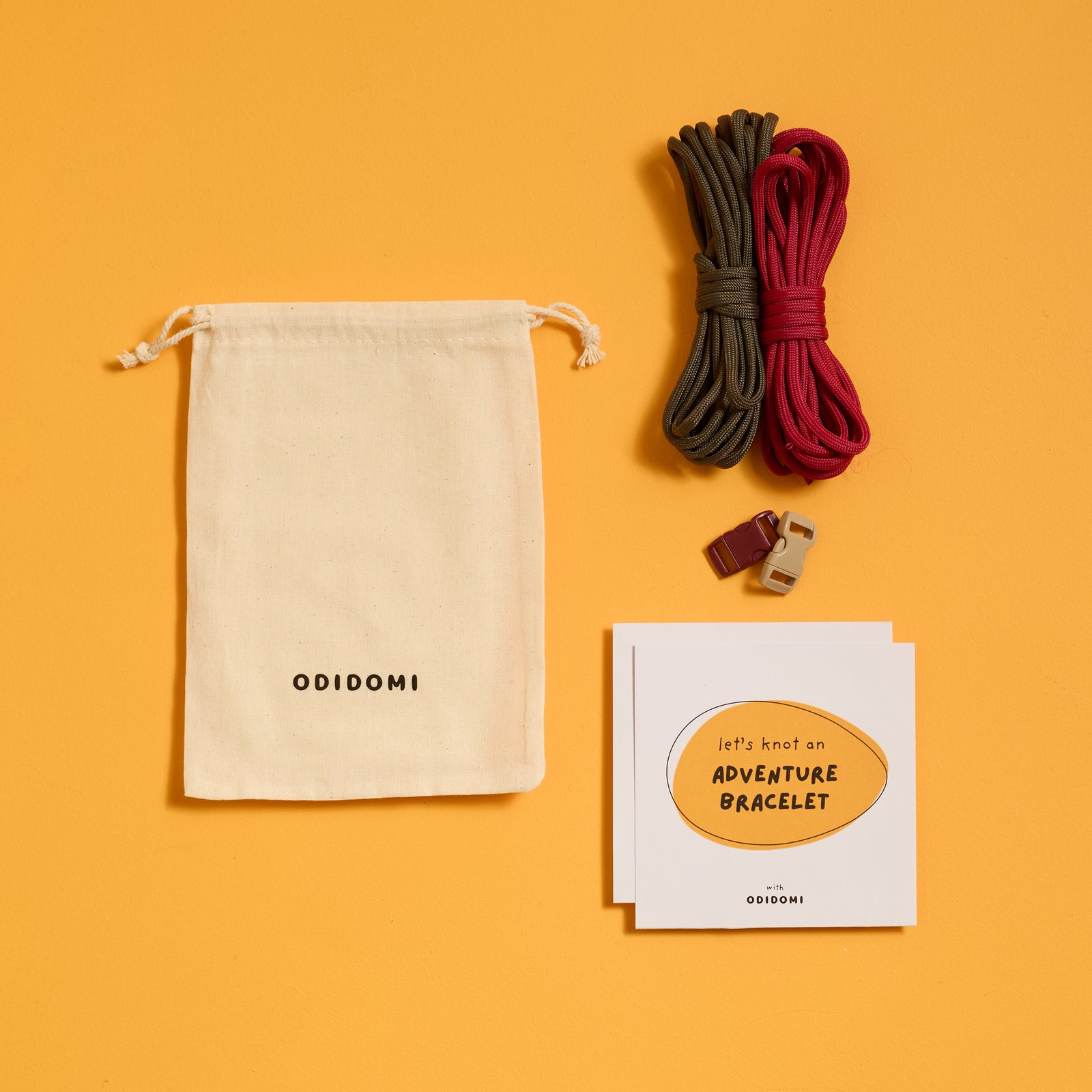 Flat lay of the complete ODIDOMI Adventure Bracelet Kit in the charcoal and red color option