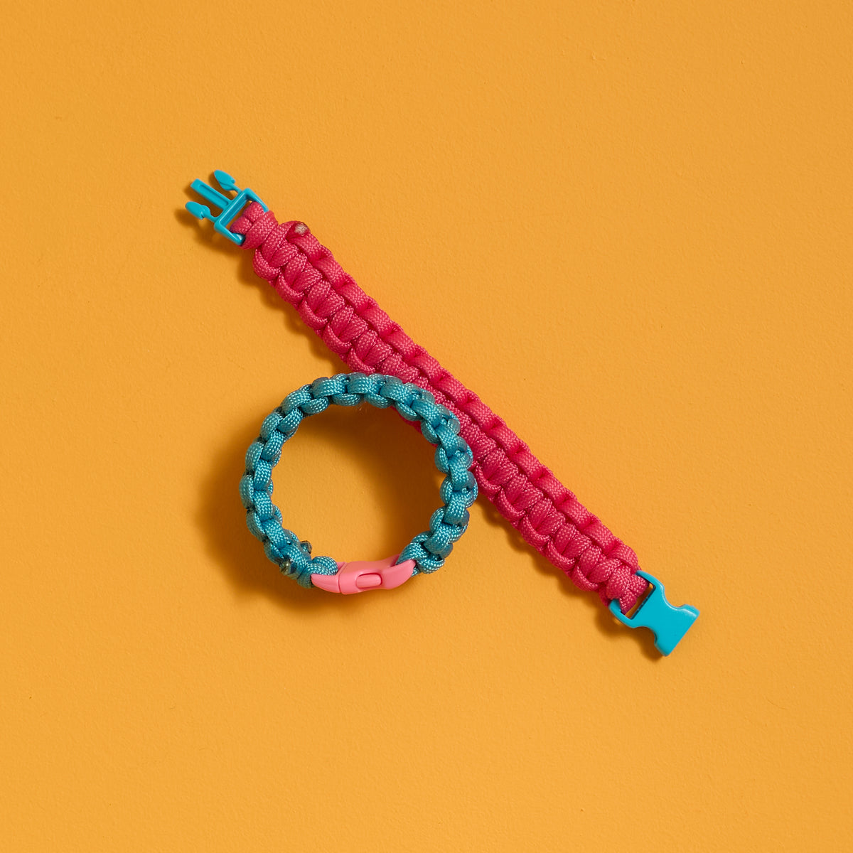 Finished pink and blue bracelets from the ODIDOMI Adventure Bracelet Kit shown flat and buckled.