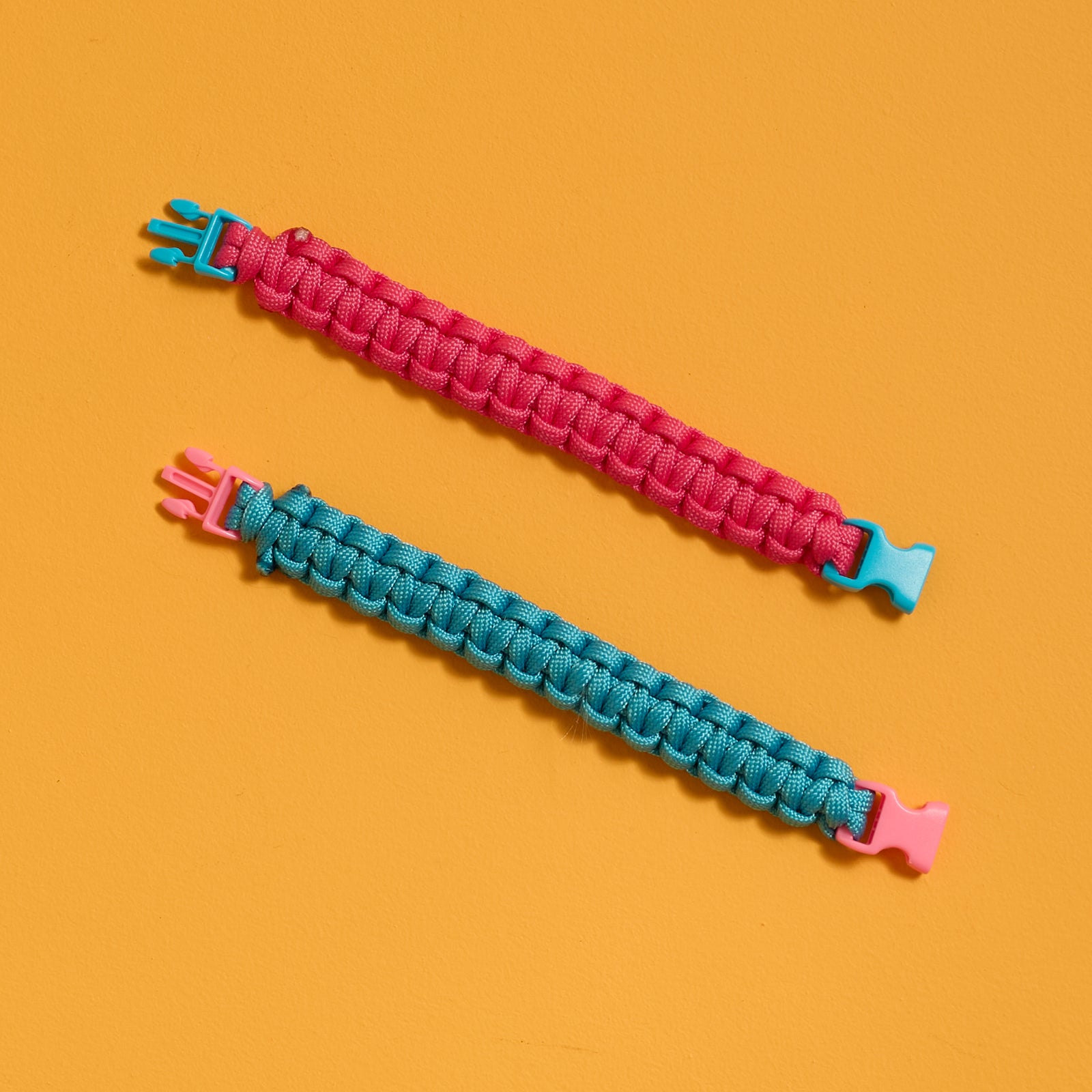 Flat view of finished bracelets from the ODIDOMI Adventure Bracelet Kit in pink and blue.