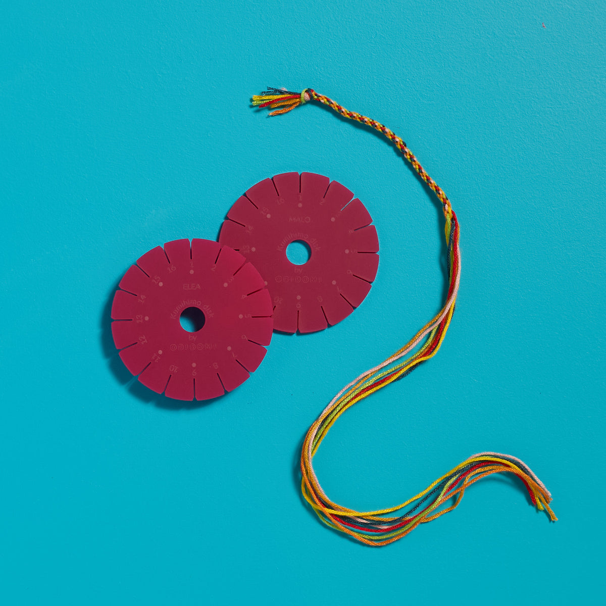 Overhead view of a half-braided friendship bracelet and personalized disk created with an ODIDOMI craft kit