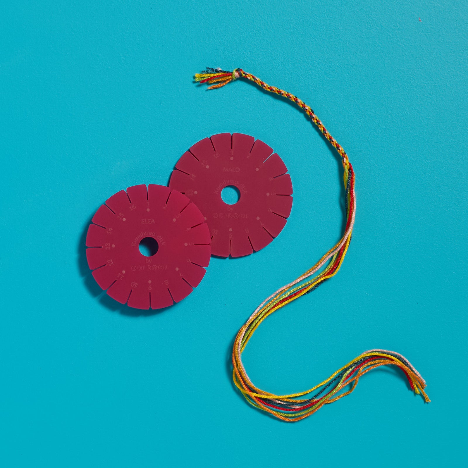 Overhead view of a half-braided friendship bracelet and personalized disk created with an ODIDOMI craft kit