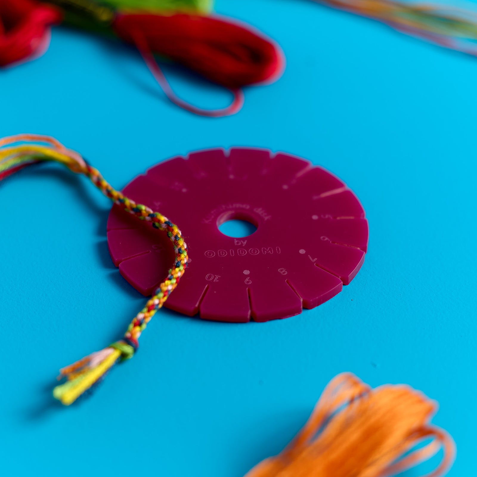 Close-up of a half-braided friendship bracelet on the braiding disk from the ODIDOMI kit.