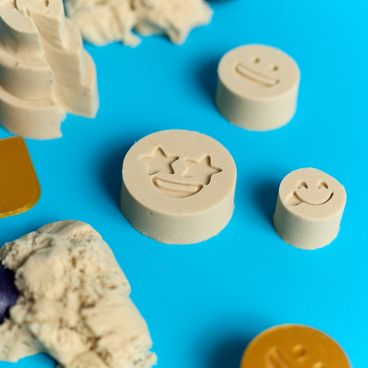 Close-up of emoji-shaped Magic Sand creations from the ODIDOMI sensory play kit.