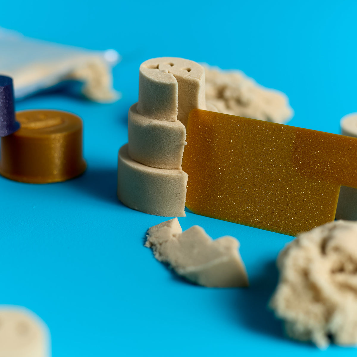 Close-up of sand cake stack and scraper tool included in the ODIDOMI Magic Sand kit.
